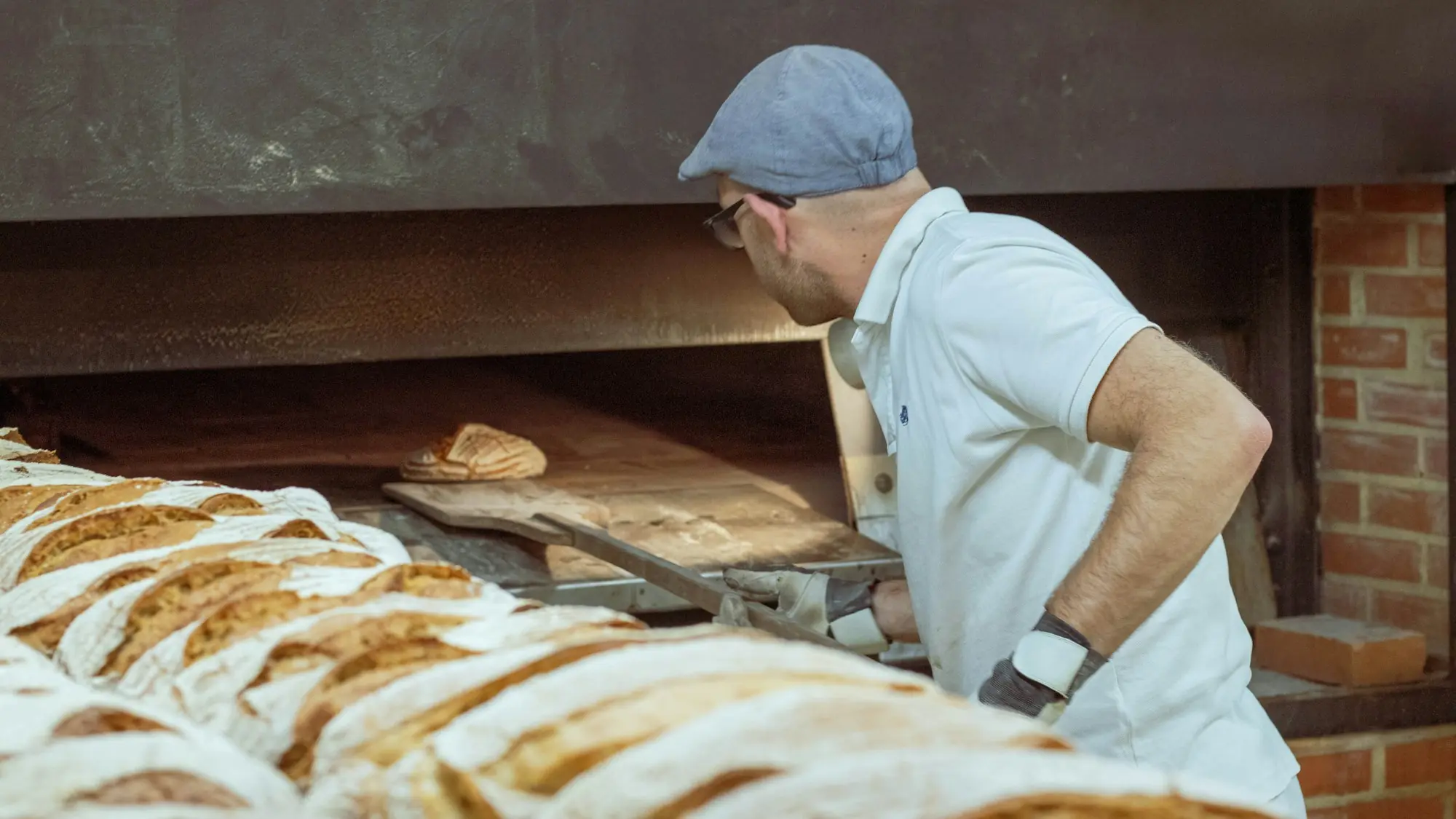 Panadero sacando una bandeja de pan del horno